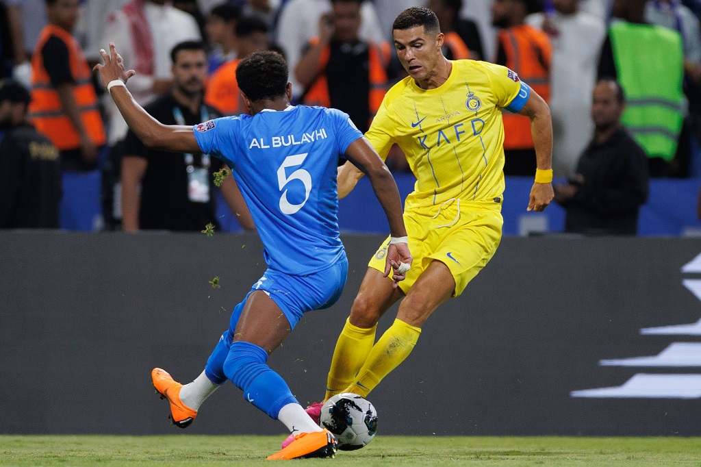 النجم البرتغالي المخضرم كريستيانو رونالدو يراوغ أحد لاعبي الهلال خلال المباراة (تصوير: أ ف ب)